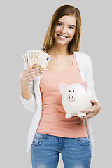 Image showing Beautiful woman putting money in a piggy bank
