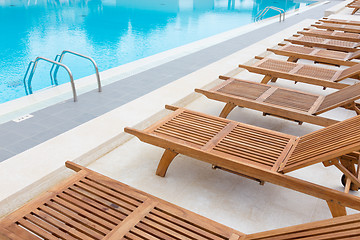 Image showing Swimming pool with wooden sunbeds.