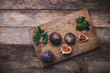 Image showing Cut Figs on chopping board and wooden table
