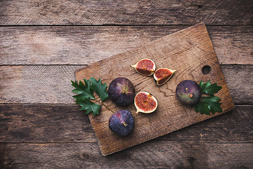 Image showing rustic style Cut figs on chopping board and wooden table