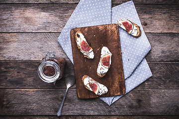 Image showing Bruschetta with cream cheese and figs on chopping board in rusti