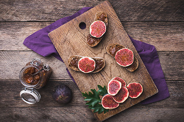 Image showing Sliced figs and bread with jam on choppingboard in rustic style