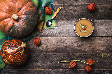 Image showing Pumpkins and soup with seeds and ground cherry on wooden table