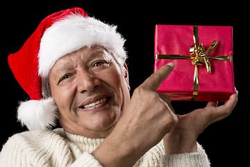 Image showing Male Senior Pointing At Red Wrapped Christmas Gift