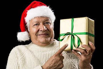 Image showing Male Senior With Santa Cap Pointing At Golden Gift