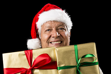 Image showing Smiling Aged Man Peeking Across Two Golden Gifts