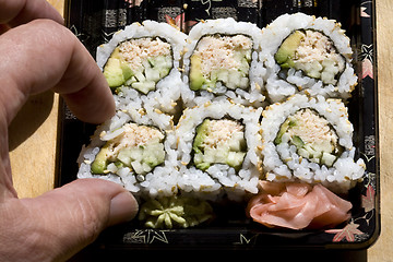 Image showing Taking One Tuna Sushi Roll