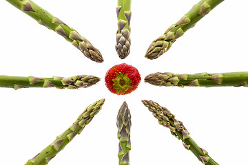 Image showing Eight Asparagus Spears Pointing at One Strawberry