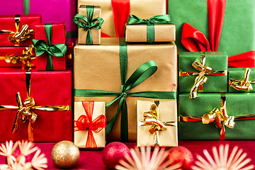 Image showing Three Piles of Xmas Gifts in Red, Gold and Green