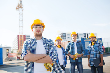 Image showing group of smiling builders in hardhats outdoors