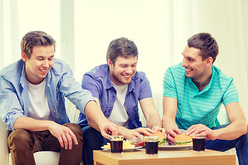 Image showing smiling friends with soda and hamburgers at home