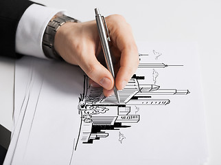 Image showing close up of male hand with pen drawing graph