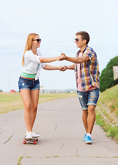 Image showing smiling couple with skateboard outdoors