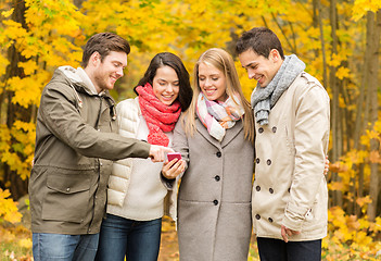Image showing smiling friends with smartphones in city park