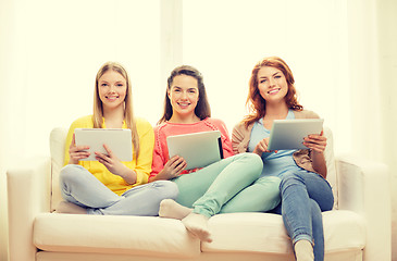 Image showing three smiling teenage girls with tablet pc at home