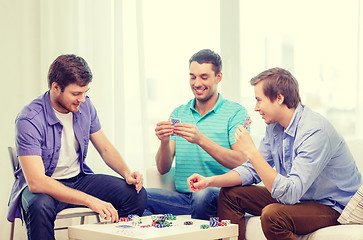 Image showing happy three male friends playing poker at home