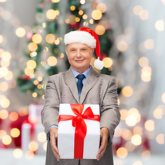 Image showing smiling man in suit and santa helper hat with gift