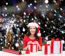 Image showing smiling woman in santa helper hats packing gifts