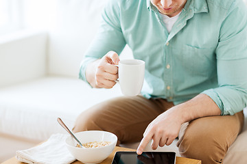 Image showing close up of man with tablet pc having breakfast