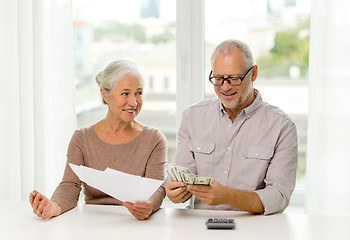 Image showing senior couple with money and calculator at home