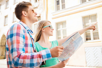 Image showing smiling couple with map and photo camera in city