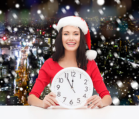 Image showing smiling woman in santa helper hat with clock
