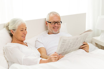 Image showing happy senior couple with newspaper in bed