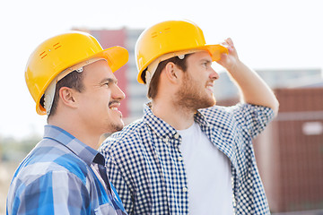 Image showing group of smiling builders in hardhats outdoors