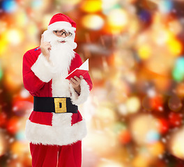 Image showing man in costume of santa claus with notepad