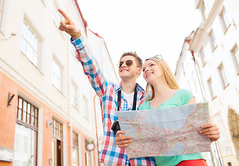 Image showing smiling couple with map and photo camera in city