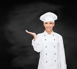 Image showing smiling female chef holding something on hand