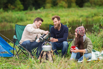Image showing group of smiling tourists cooking food in camping