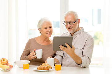 Image showing happy senior couple with tablet pc at home