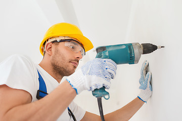 Image showing builder in hardhat working with drill indoors