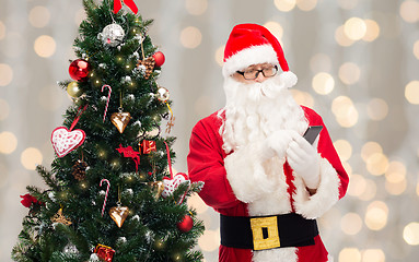Image showing santa claus with smartphone and christmas tree