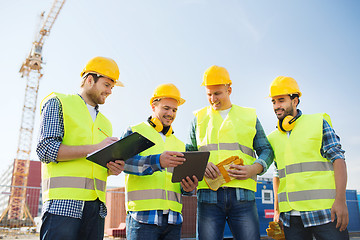 Image showing group of smiling builders with tablet pc outdoors