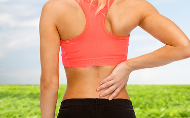 Image showing close up of sporty woman touching her back