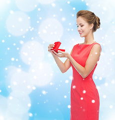 Image showing smiling young woman in red dress with gift box