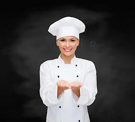 Image showing smiling female chef holding something on hands