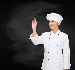 Image showing smiling female chef writing something on air