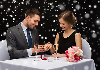 Image showing smiling couple with red gift box at restaurant