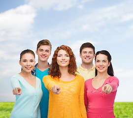 Image showing group of smiling teenagers over blue sky and grass