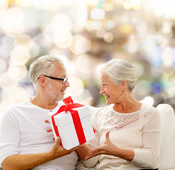 Image showing happy senior couple with gift box at home