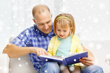 Image showing smiling father and daughter with book at home