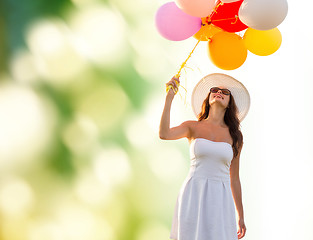 Image showing smiling young woman in sunglasses with balloons