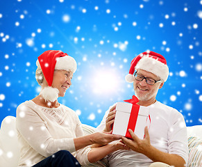 Image showing happy senior couple in santa hats with gift box