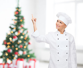 Image showing smiling female chef pointing finger to something