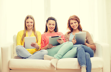 Image showing three smiling teenage girls with tablet pc at home