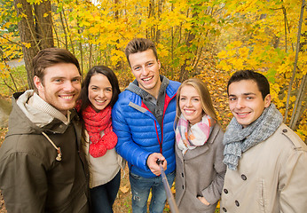 Image showing smiling friends taking selfie in autumn park