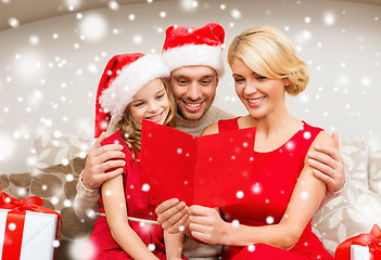 Image showing smiling family in santa hats reading postcard